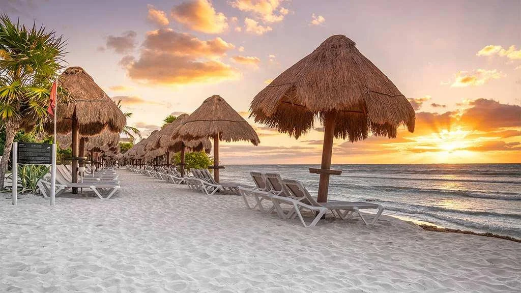 La playa del Caribe con palapas y luz de amanecer